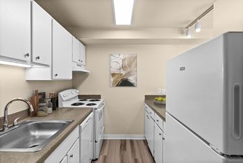 A kitchen with white cabinets and a white fridge.