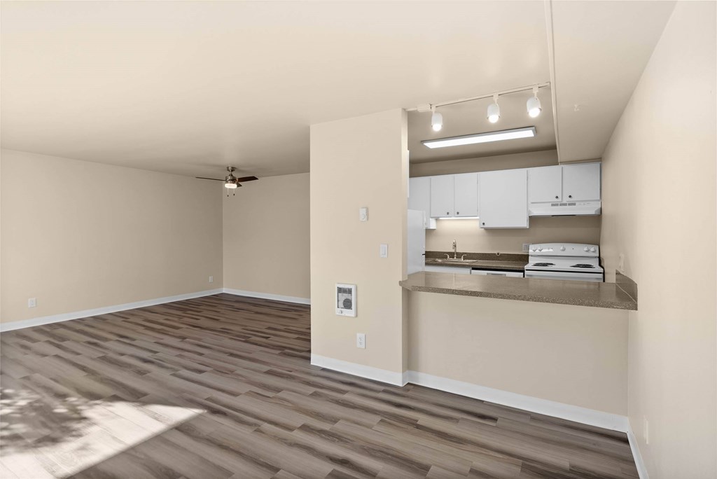 A room with a ceiling fan and a kitchenette area.