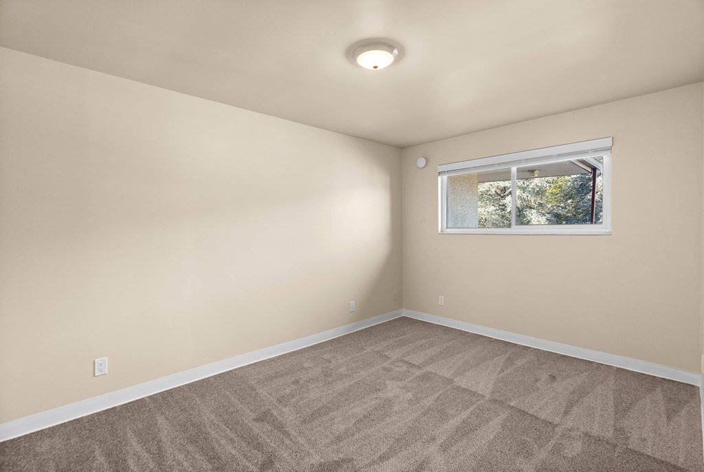 A room with a window and carpeted floor.