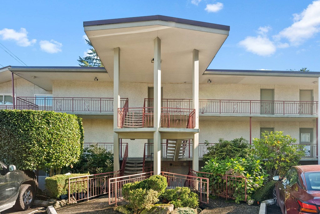A white building with a red car parked in front.