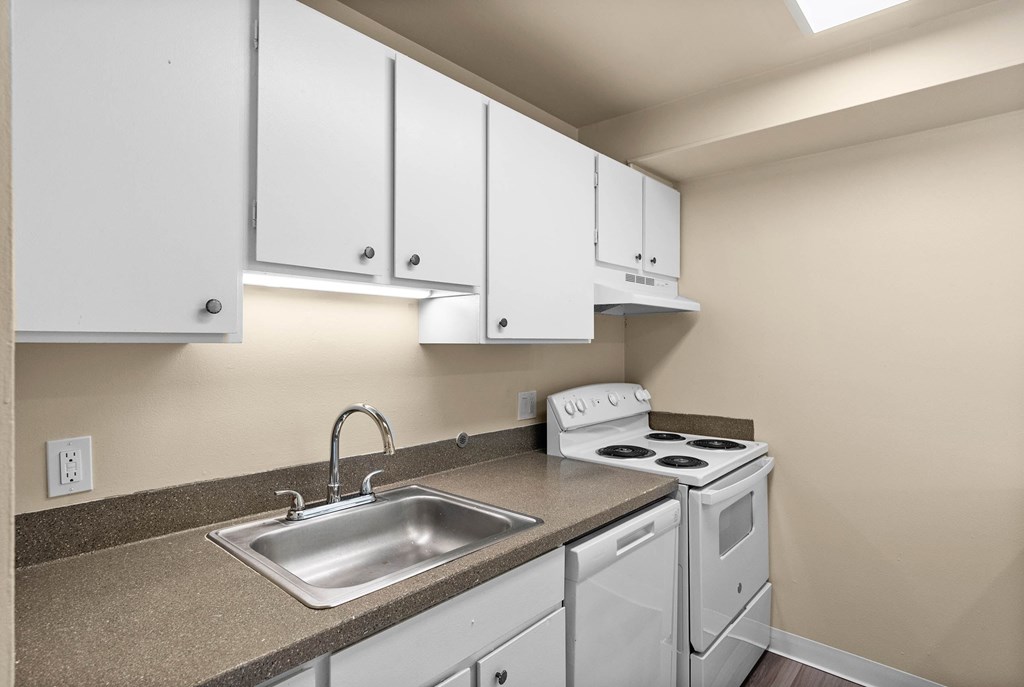 A kitchen with white cabinets and a stove top oven.