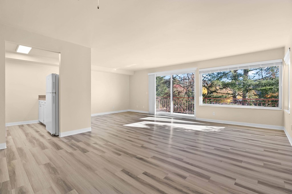 A room with wooden flooring and a large window overlooking a residential area.
