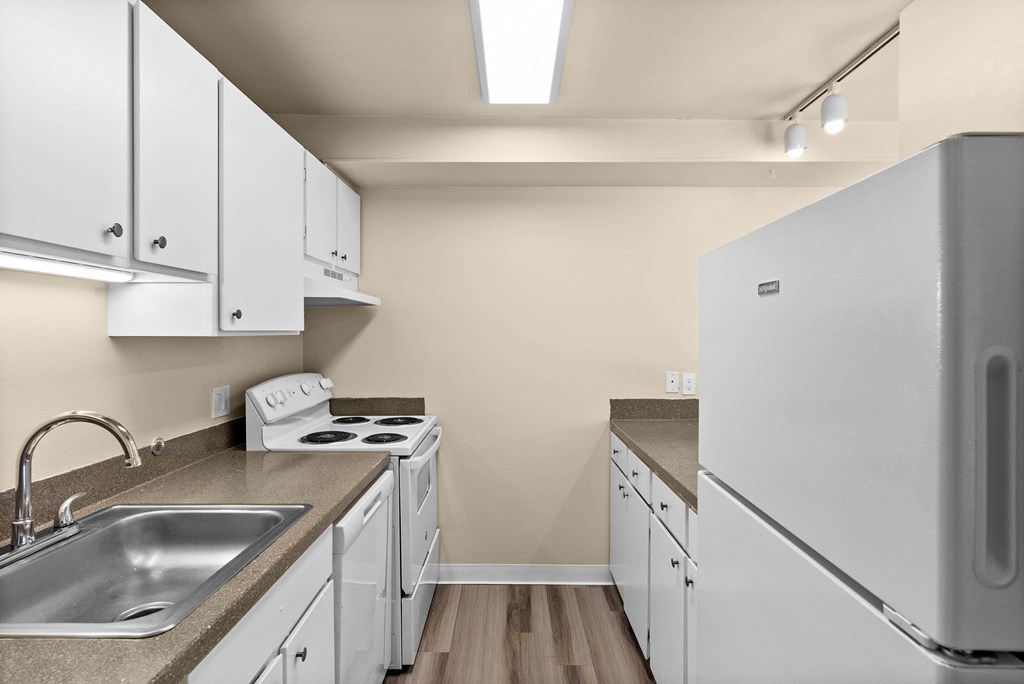 A kitchen with white cabinets and a white refrigerator.
