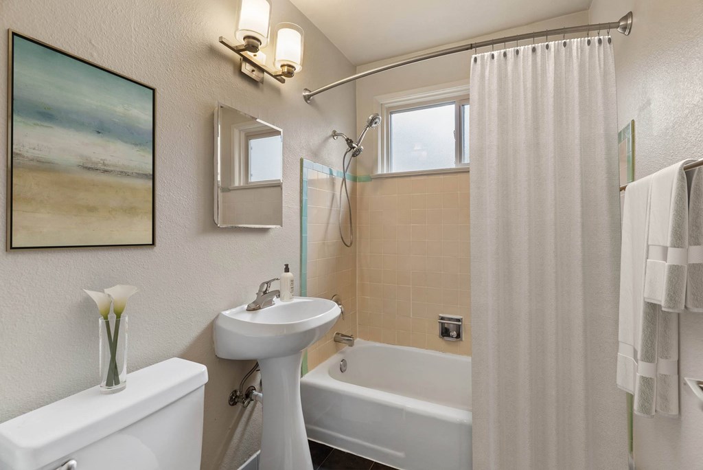 A bathroom with a white sink, toilet, and bathtub.