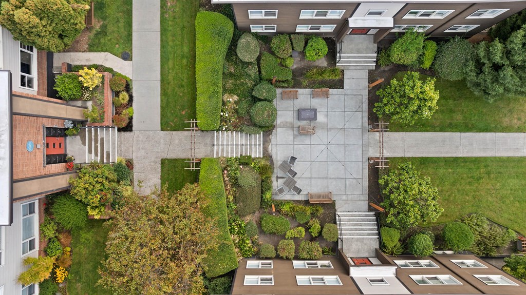 A courtyard surrounded by buildings with a bench and a table in the middle.