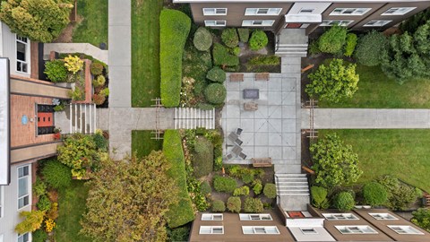 A courtyard surrounded by buildings with a bench and a table in the middle.