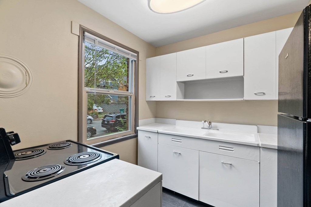 A kitchen with a stove top oven and white cabinets.