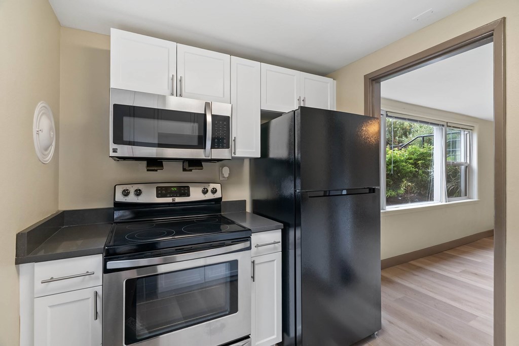 A black refrigerator stands next to a stove in a kitchen.