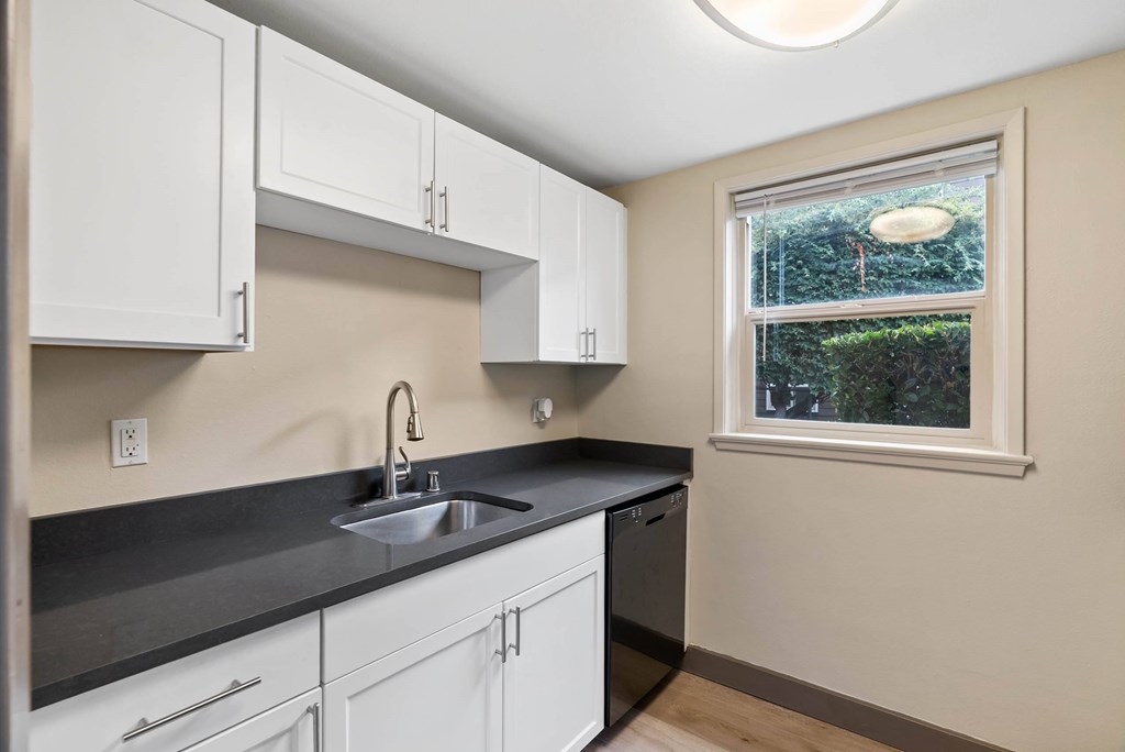 A kitchen with white cabinets and a black countertop.