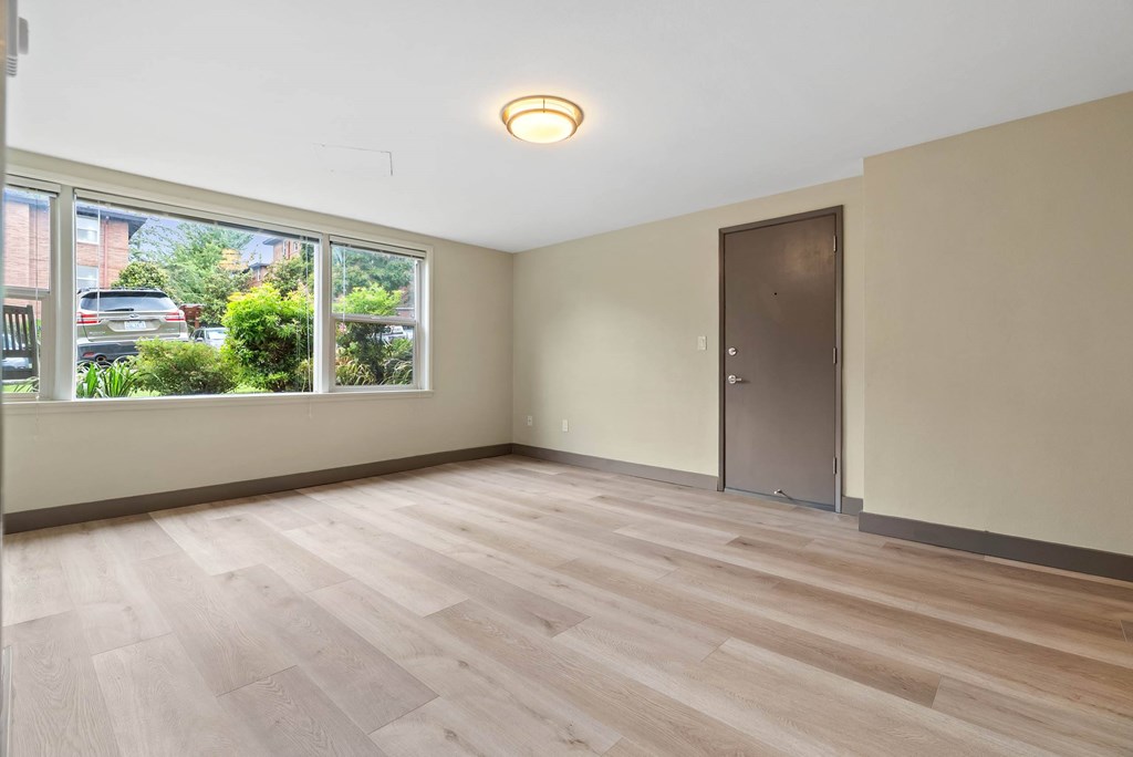 A room with wooden flooring and a window overlooking a street.