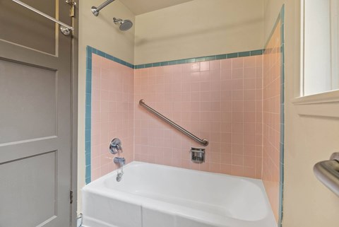A white bathtub with a shower head and a shower hose.