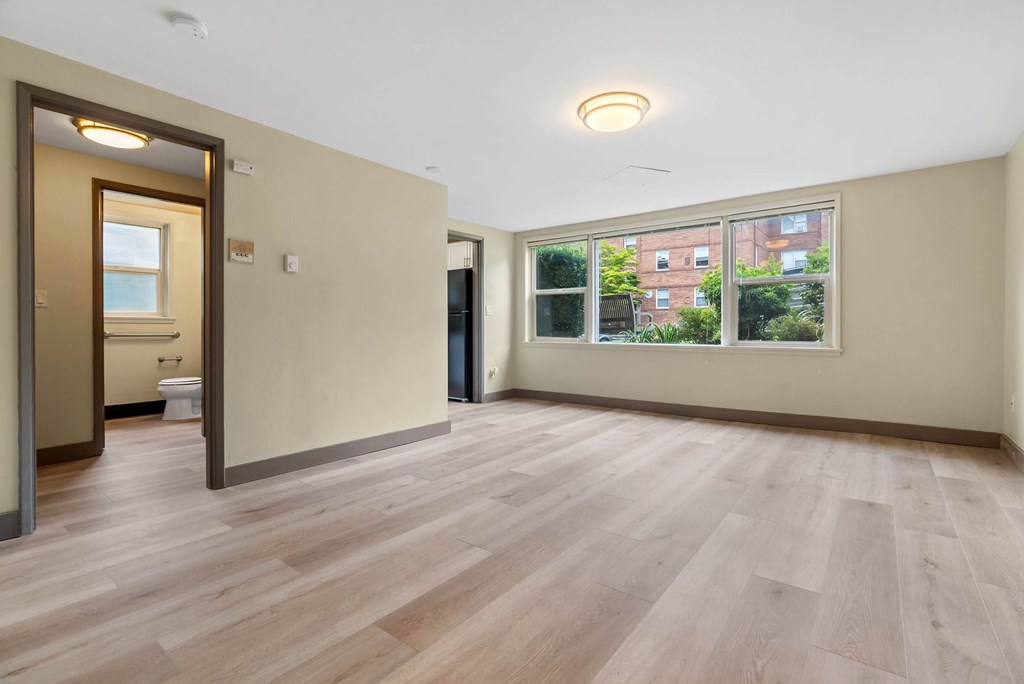 A room with wooden flooring and a window showing a view of a building outside.