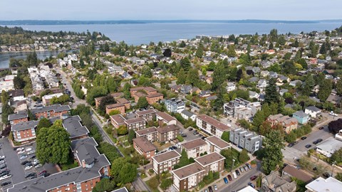 A bird's eye view of a residential area with houses and a body of water in the distance.
