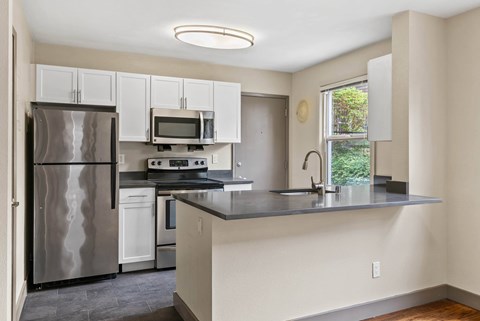 A kitchen with a refrigerator, microwave, oven, and sink.