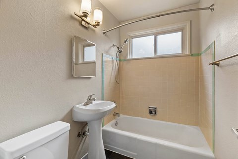 A white sink and toilet in a bathroom with a glass shower door.