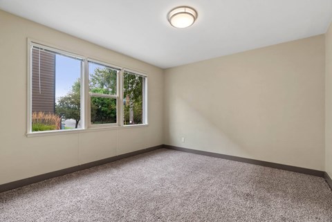 A room with a carpeted floor, a window, and a ceiling light.