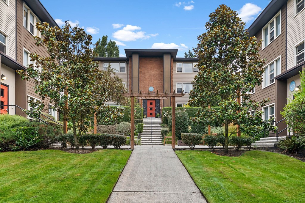 A building with a red door is surrounded by trees and bushes.