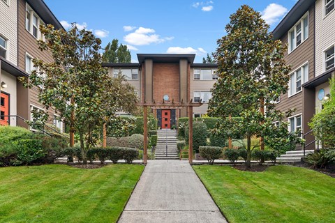 A building with a red door is surrounded by trees and bushes.