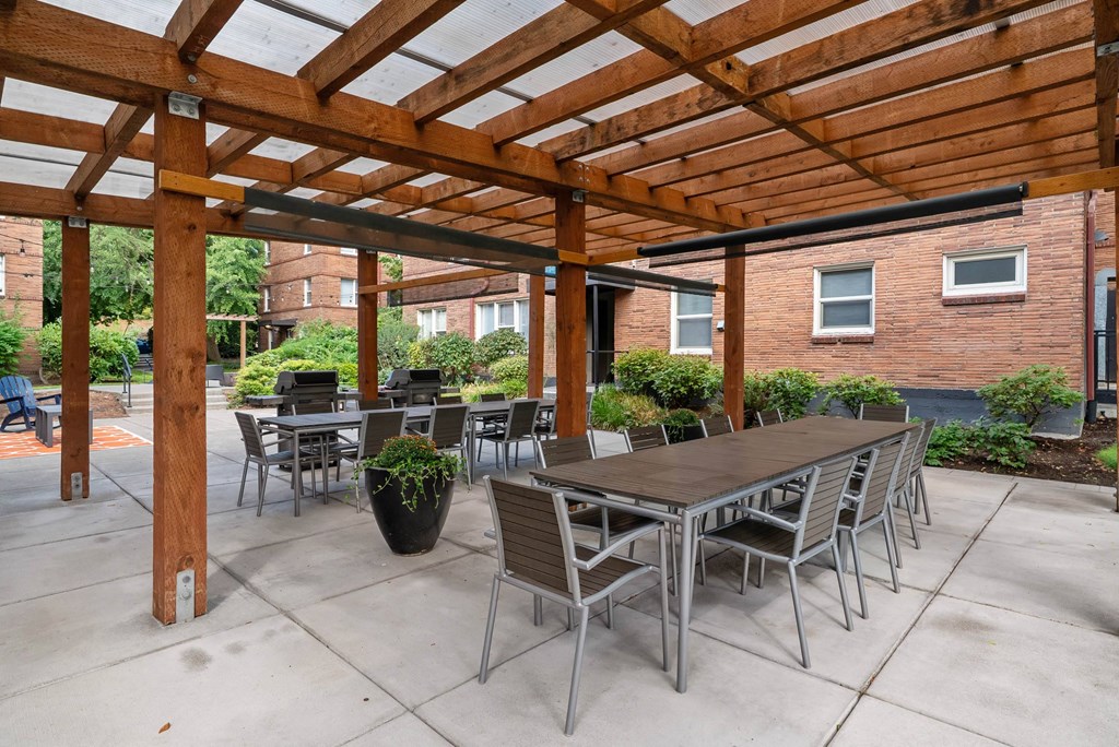 A wooden pergola with a table and chairs underneath.