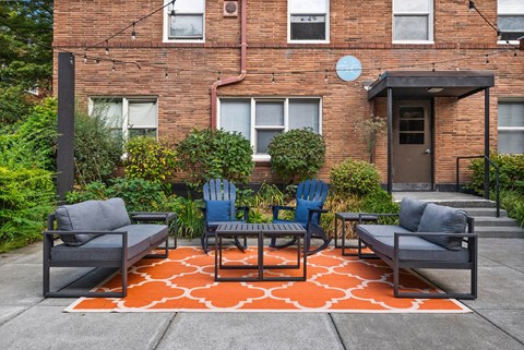 A patio with a table and chairs in front of a brick building.