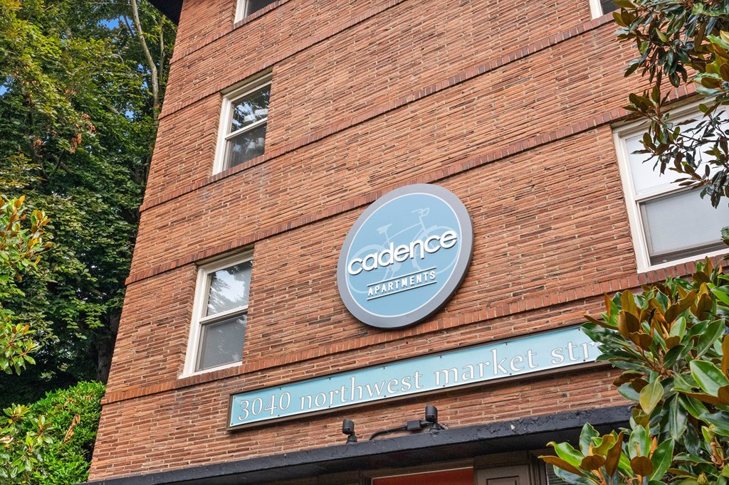 A red brick building with a sign that says "Cadence Apartments" and "3010 Northwest Market St."