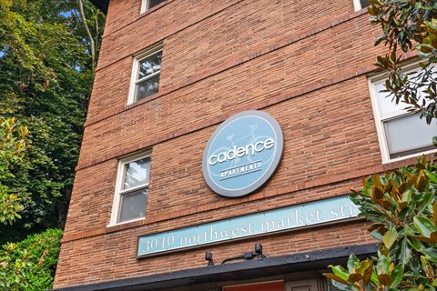 A red brick building with a sign that says "Cadence Apartments" and "3010 Northwest Market St."