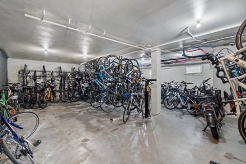 A large collection of bicycles are stored in a spacious garage.