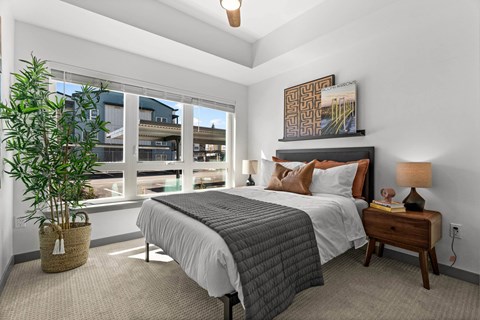 A bedroom with a large bed and a potted plant.