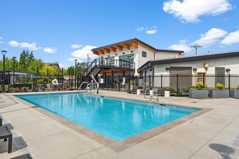 A large swimming pool in front of a building with a black fence around it.