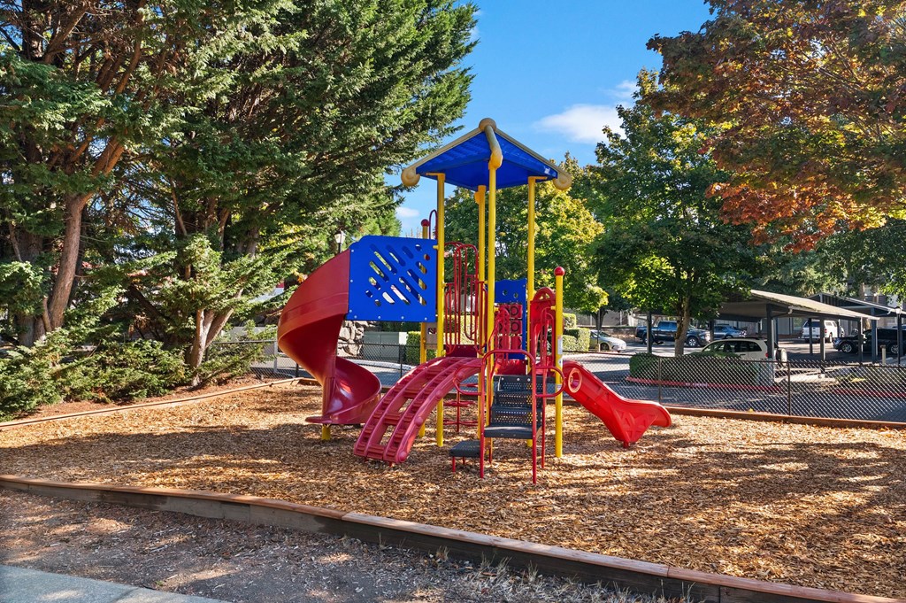 A playground with a red slide and a blue and yellow structure.