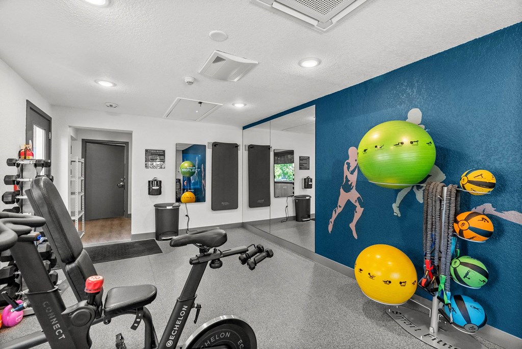 A gym room with exercise equipment and a blue wall with drawings of lemons.