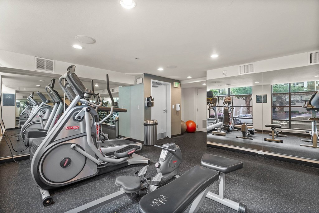 A gym with a variety of equipment including treadmills, stationary bikes, and weight machines.