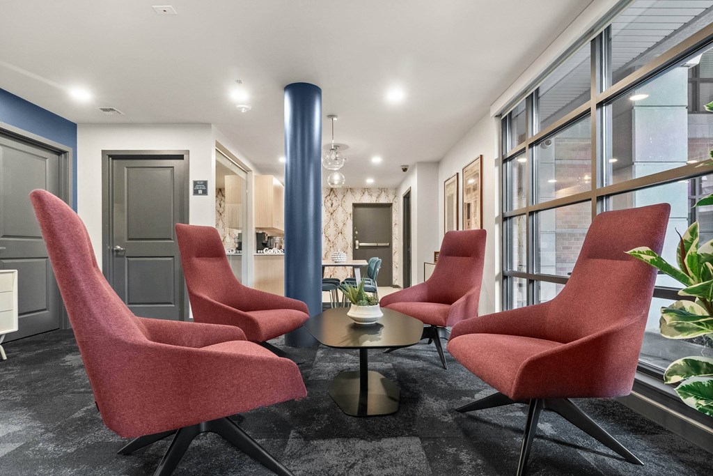 A room with red chairs and a round table.