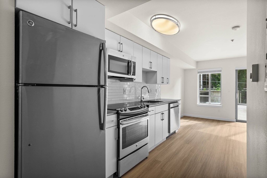 A modern kitchen with a refrigerator, microwave, oven, and sink.