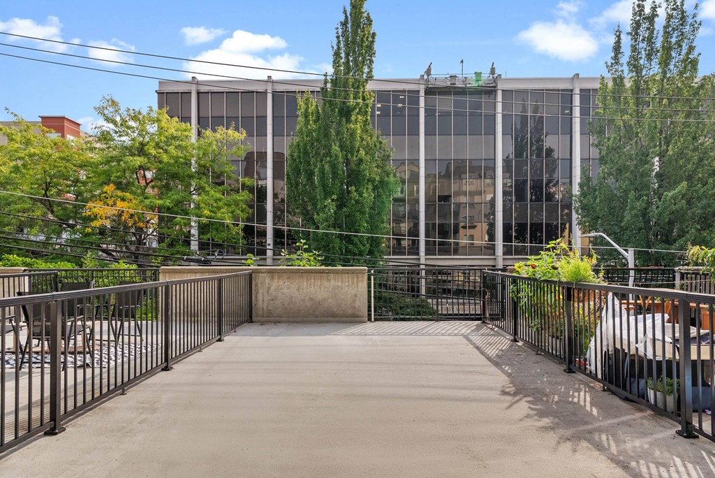A modern building with a glass facade is surrounded by trees and a metal fence.
