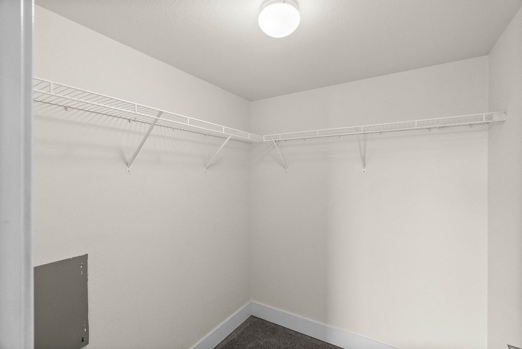 A white room with a shelf and a light on the ceiling.
