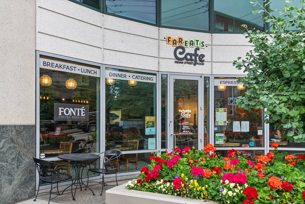 A restaurant named Fareatis Cafe with a signboard and flower bed in front.