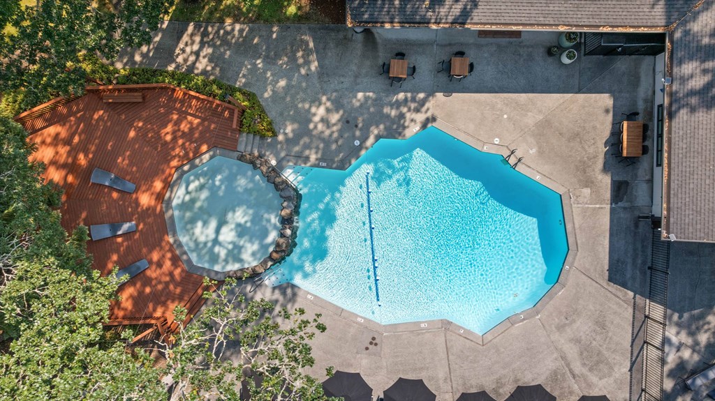 A large swimming pool surrounded by a concrete floor and a wooden deck.