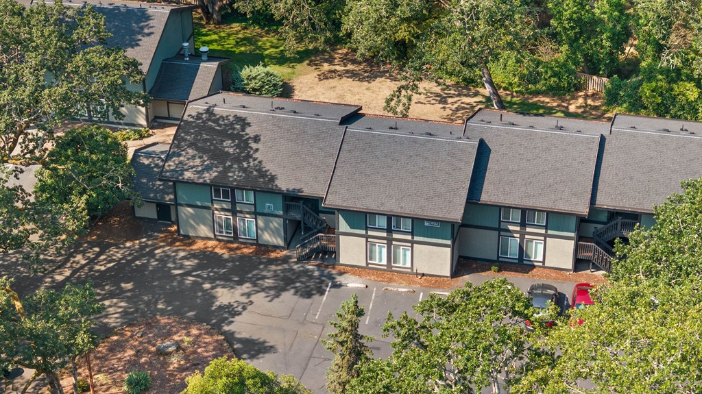A large building with a grey roof surrounded by trees.