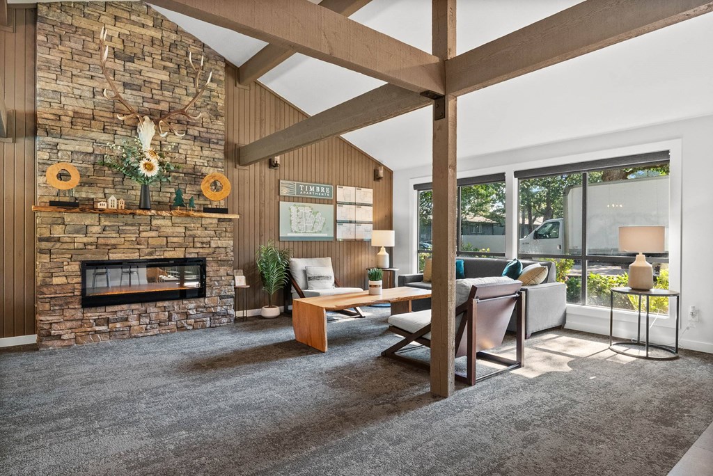 A living room with a stone fireplace and a wooden ceiling.
