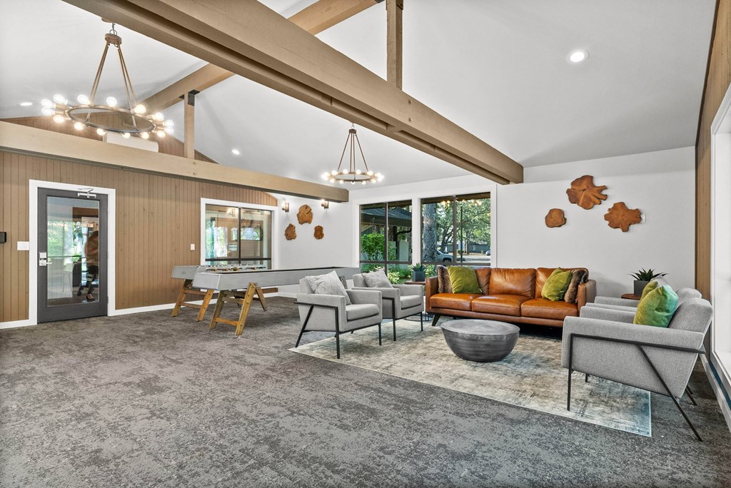 A modern living room with a grey carpet and wooden beams on the ceiling.