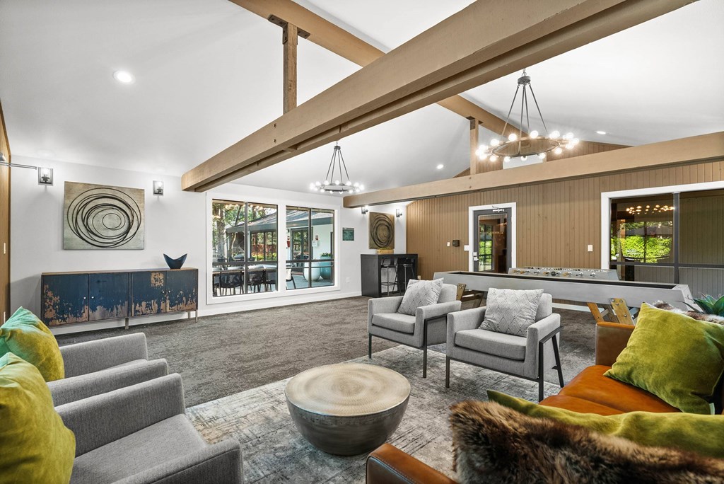 A living room with a grey couch, a green cushion, a wooden table and a painting on the wall.