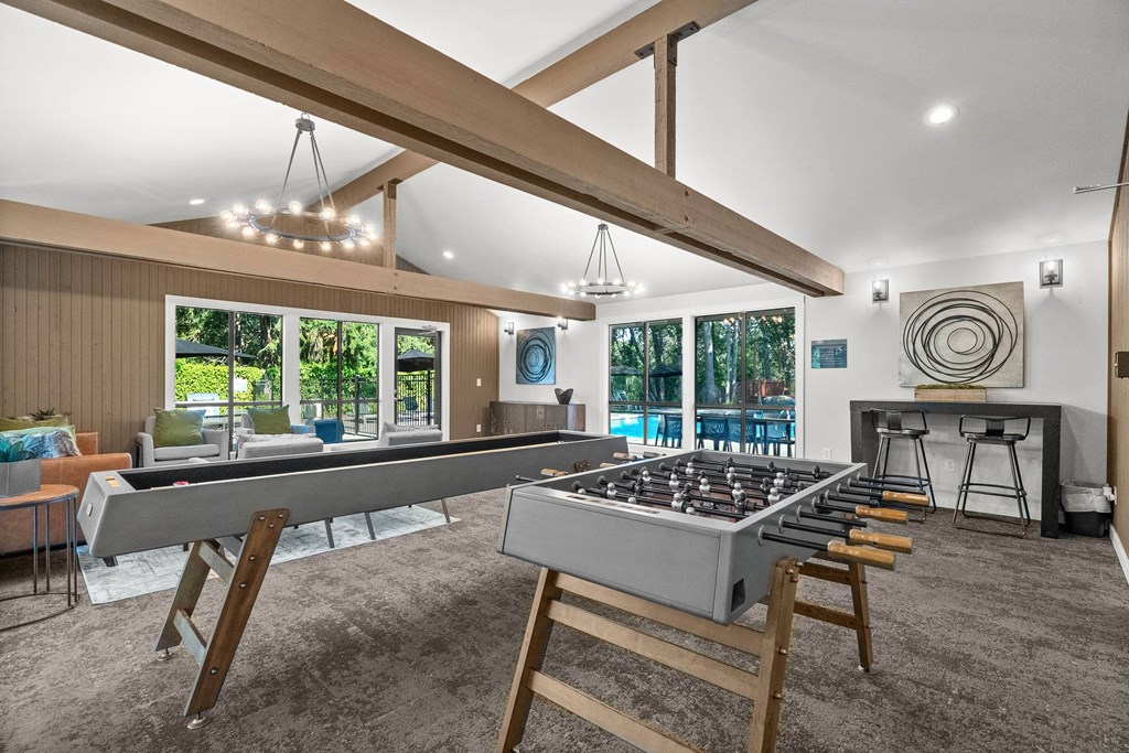 A billiard table is in the middle of a room with a pool table and a foosball table.