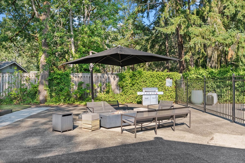 A black umbrella shades a table and chairs in a gravel courtyard.