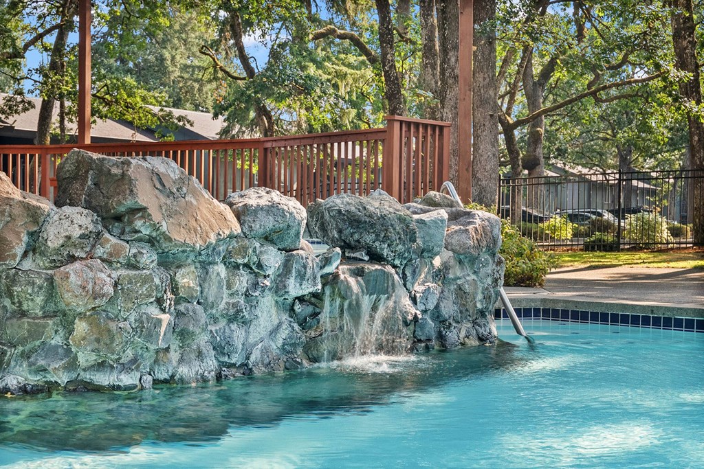 A pool with a rock wall and waterfall.