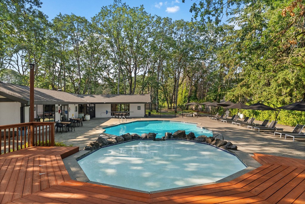 A wooden deck surrounds a small pool in a backyard.