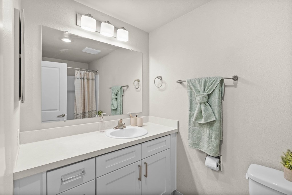A bathroom with a white counter and a green towel.