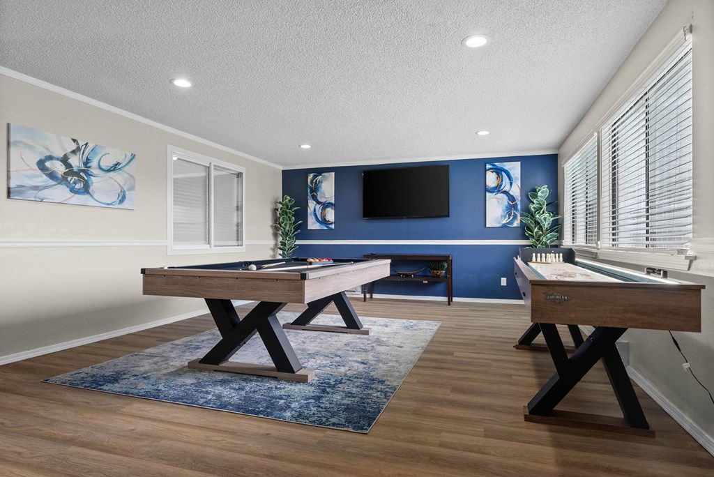 A room with a pool table and a TV mounted on the wall.