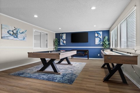 A room with a pool table and a TV mounted on the wall.