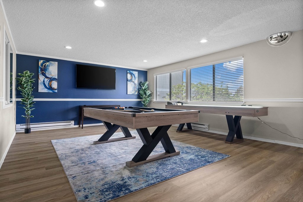 A room with a pool table and a tv on the wall.